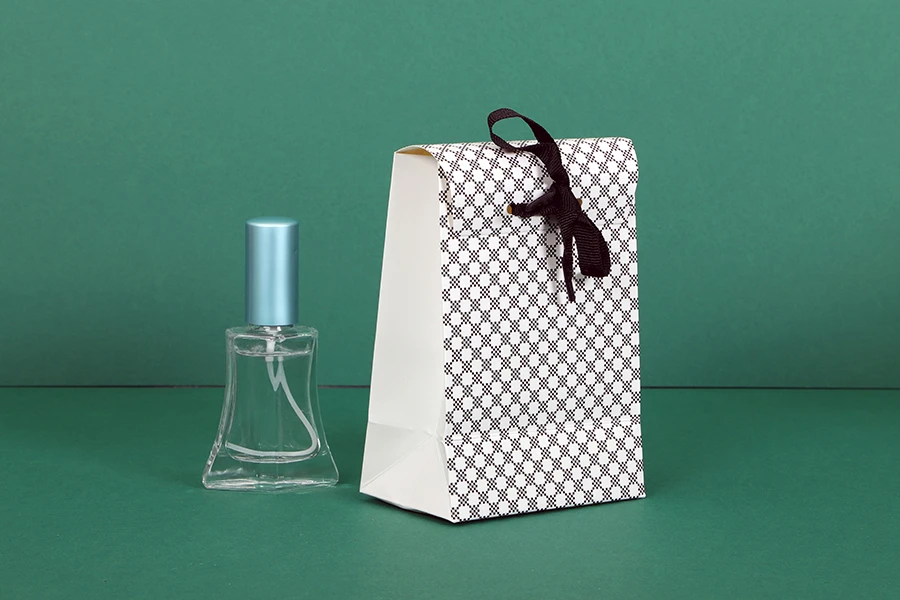 Paper gift bag in a special design and print with a 10mm grosgrain ribbon bow tie handle in size 105x67x150 Paper gift bag in a special design and print with a 10mm grosgrain ribbon bow tie handle in size 105x67x150