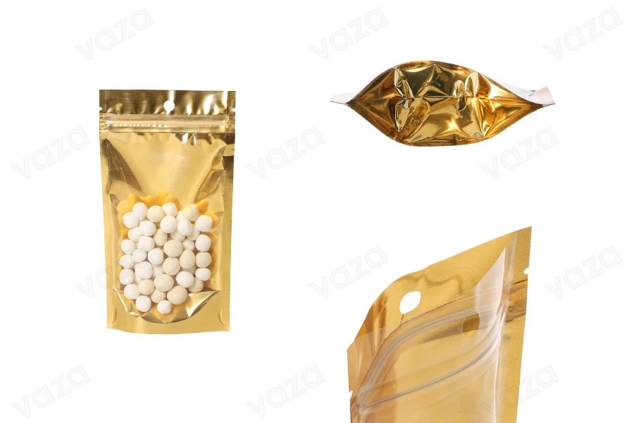 Qese tip Doy Pack 100x30x180 mm prej alumini, me pjesën e pasme të artë dhe pjesën e përparme të transparente, me mbyllje “zip” dhe mundësi vulosjeje me nxehtësi – 100 copë. Qese tip Doy Pack 100x30x180 mm prej alumini, me pjesën e pasme të artë dhe pjesën e përparme të transparente, me mbyllje “zip” dhe mundësi vulosjeje me nxehtësi – 100 copë.-imazh_produkt